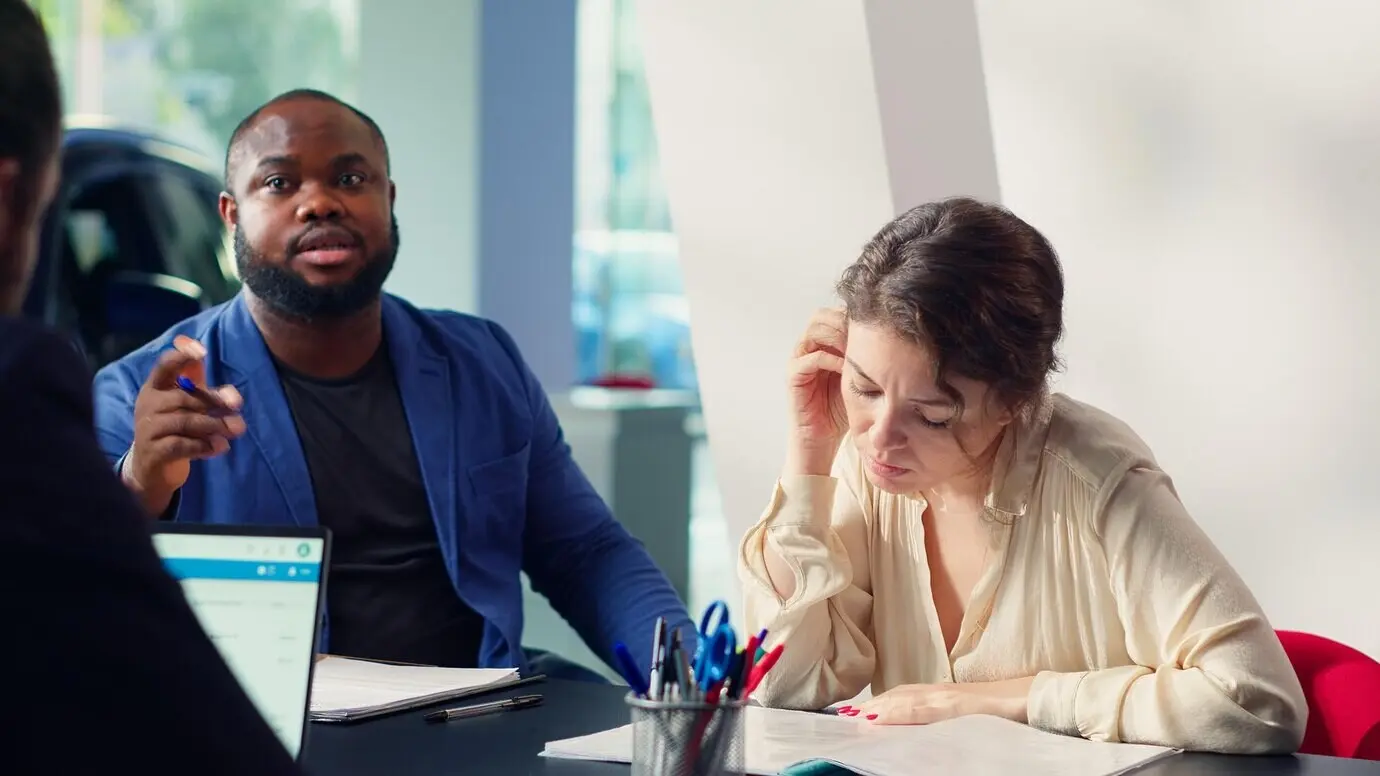 Клиенты дилерского центра читают условия и положения контракта.